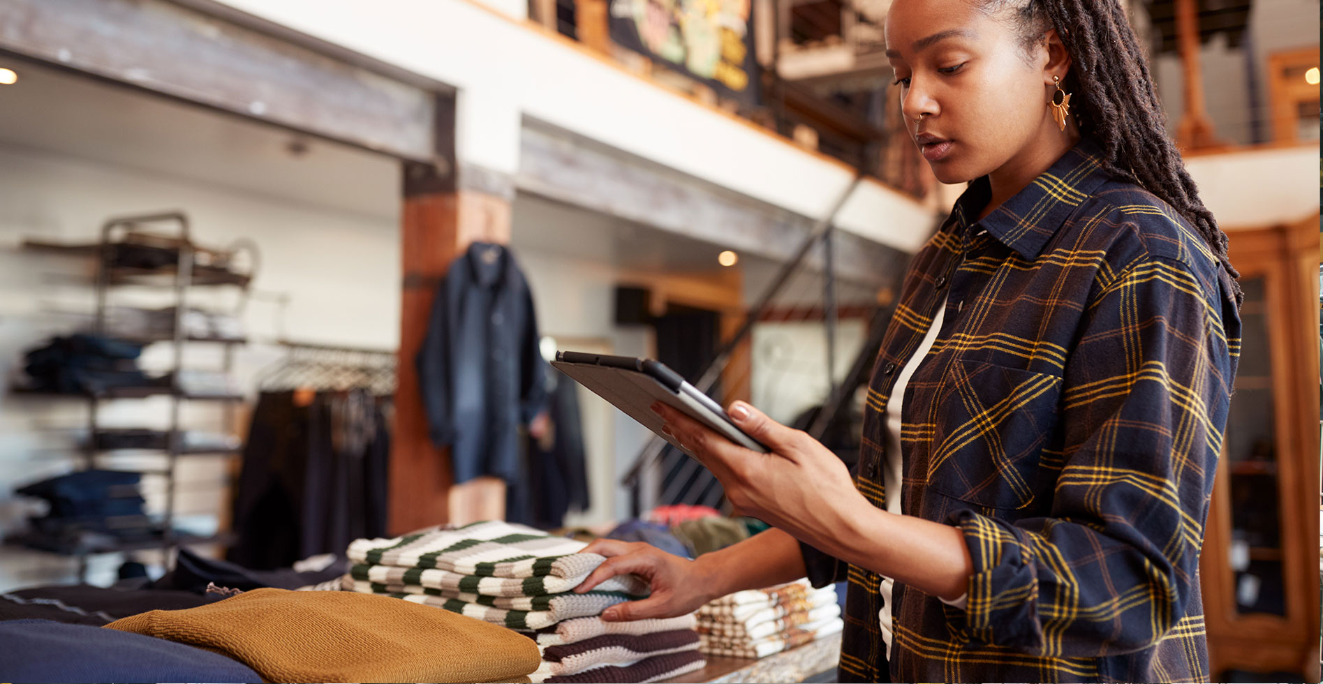 a female apparel store owner is checking her inventory on a tablet